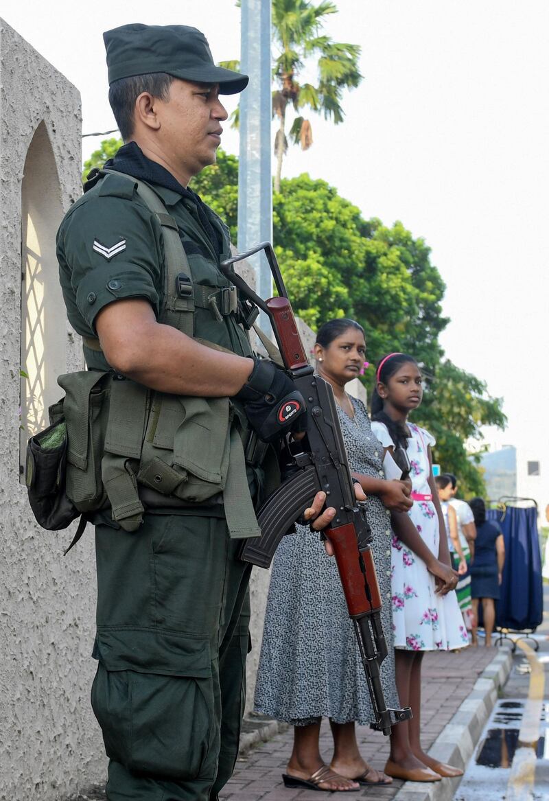 A Sri Lankan Army soldier (L) stands guard outside the St. Theresa's church as the Catholic churches hold services again after the Easter attacks in Colombo on May 12, 2019. Thousands of Catholics attended mass in Sri Lanka's capital Colombo on May 12 amid tight security to prevent a repeat of Easter bomb attacks that killed 258 people. / AFP / LAKRUWAN WANNIARACHCHI
