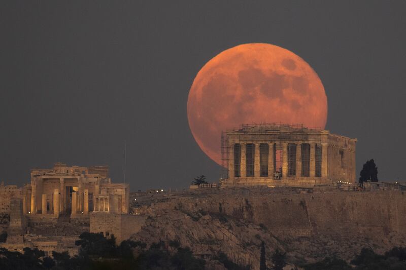 The Full Moon rises behind the Acropolis hill and the ancient Parthenon Temple, in Athens. AP