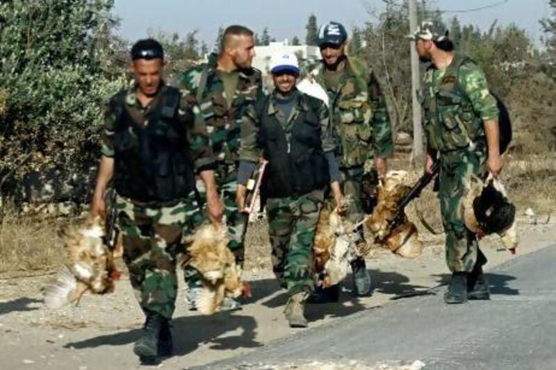 Syrian army soldiers carry chickens in the village of Buweida, north of Qusayr, in central Homs province on Friday. AFP
