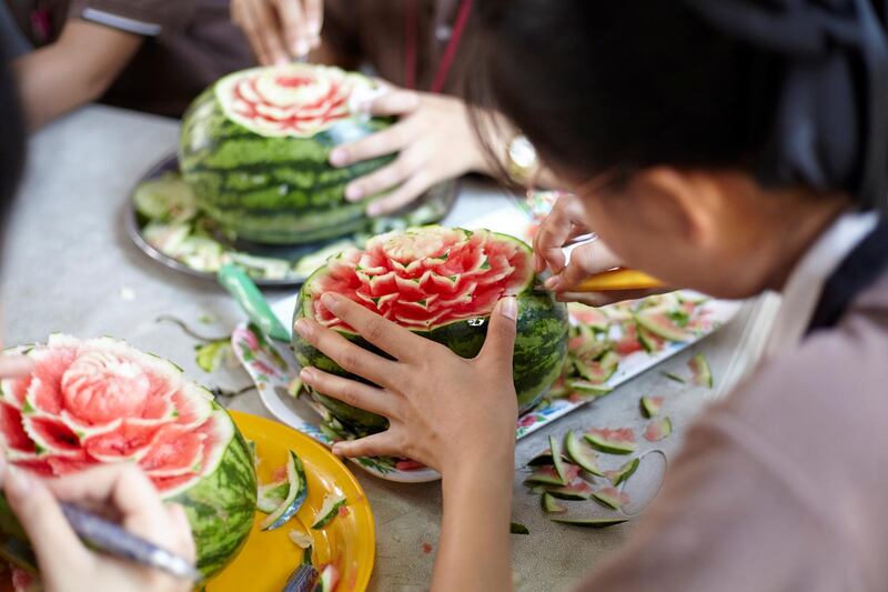 Bangkok-Thailand-CLC (Community Learning Center) Temple of Dawn- Close up of student hands craving on the water melon. Sasamon Rattanalangkarn for The National