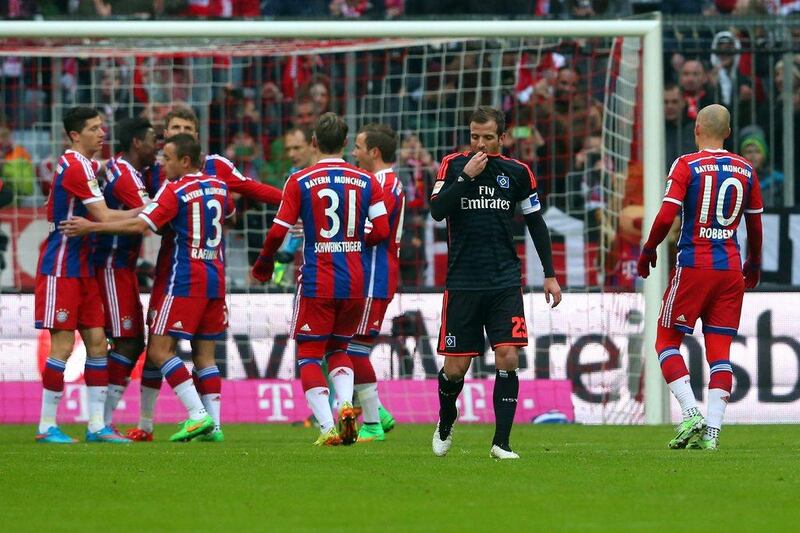 Bayern Munich players celebrate with goal-scorer Thomas Mueller while Hamburg captain Rafael van der Vaart looks on. Alexander Hassenstein / Getty Images