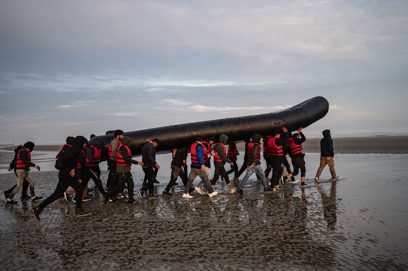 Migrants carry a smuggling boat on their shoulders on a beach in northern France in October. AFP