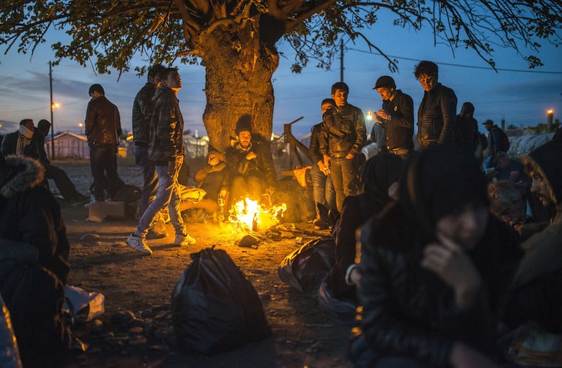 Migrants and refugees keep warm around a bonfire as they wait to enter a registration camp after crossing the Greek-Macedonian border near Gevgelija in 2017. AFP