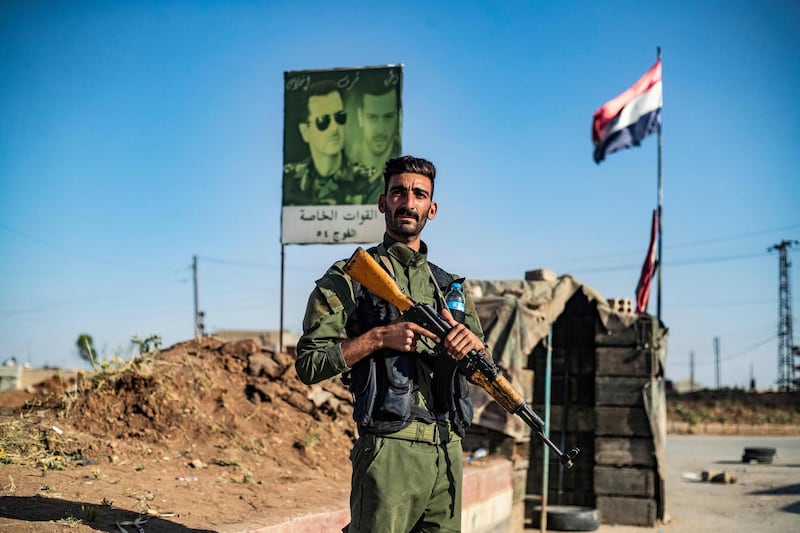 A member of the Syrian Kurdish internal security services known as "Asayish" stands at a joint checkpoint with Syrian government forces in the al-Tay neighbourhood of Syria's northeastern city of Qamishli on April 27, 2021, after the implementation of Russian-brokered ceasefire agreement.  / AFP / DELIL SOULEIMAN
