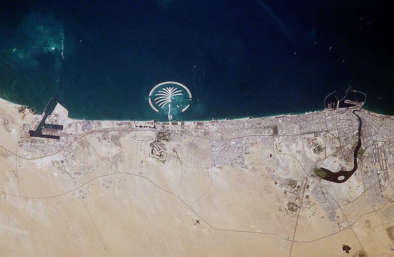 This NASA file image obtained 13 July, 2003, captured by the crew of the International Space Station in March, 2003, shows Palm Island (C) along the coast of Dubai in the United Arab Emirates. Palm Island Resort, just 1 mile off the coast from Dubai, is scheduled to be complete by 2006. Advertised as being visible from the Moon this man-made structure will have 17 huge fronds surrounded by a crescent-shaped breakwater. This island is being built from 80 million cubic meters (2.8 billion cubic feet) of land dredged from the approach channel to the Emirate's Jebel Ali port, which is being deepened to 17 meters (56 feet). Sediments in the water from dredging activity can be seen near the port. Palm Island is one of several massive projects in Dubai aimed at diversifying the economic base by expanding the tourist industry. The government of Dubai predicts that tourism, mostly from Europe, will quadruple to 15 million visitors annually by 2010. When completed the resort will have approximately 1200 single-family residences each with private beach front, 600 multi-family residences, an aquatic theme park, shopping centers, cinemas, and more. A twin island is planned to be built nearby.     AFP PHOTO/NASA (Photo by NASA / NASA / AFP)