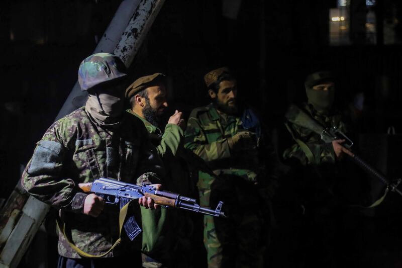 Taliban fighters stand guard at the scene of the bomb blast. EPA