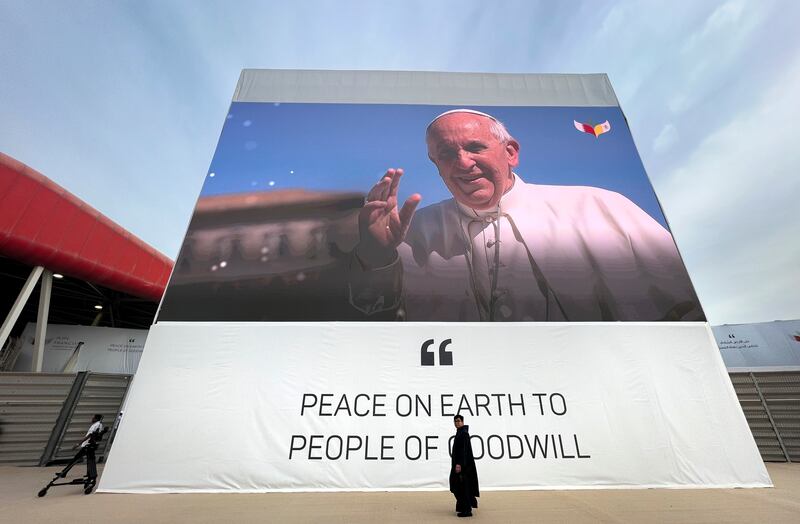 A priest passes under a giant poster of Pope Francis in Bahrain. AP Photo