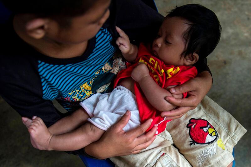 A young flood victim cradles a baby as they take shelter in a school compound in Sanamxai, Attapeu province. AFP