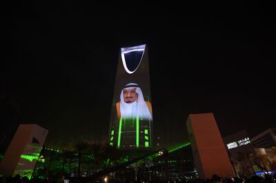 People watch a projection depicting a portrait of King Salman bin Abdulaziz al-Saud during an event in the capital Riyadh on late September 23, 2017 commemorating the anniversary of the founding of the kingdom.
The national day celebration coincides with a crucial time for Saudi Arabia, which is in a battle for regional influence with arch-rival Iran, bogged down in a controversial military intervention in neighbouring Yemen and at loggerheads with fellow US Gulf ally Qatar. / AFP PHOTO
