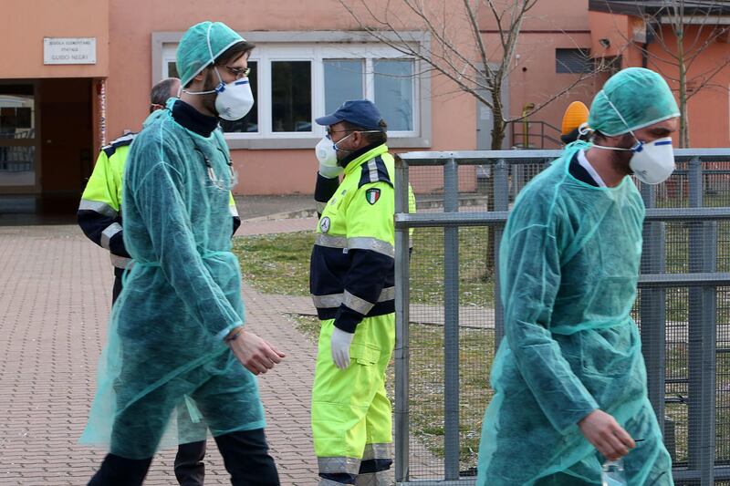 Medical workers in protective gear work outside a closed school in Vo' Euganeo, Padova, Italy, on Sunday. EPA