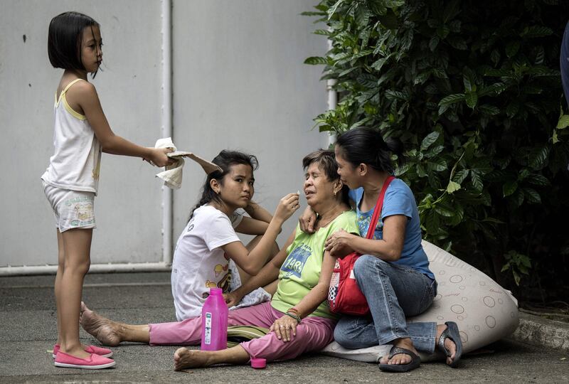 An elderly woman (C) is comforted after residents were evacuated from a fire that engulfed an informal settlers area beside a river in Manila on August 11, 2017.
Fires are common hazards in the sprawling capital, where millions live in hovels made of scrap wood and cardboard and fire safety regulations are rarely imposed. / AFP PHOTO / NOEL CELIS