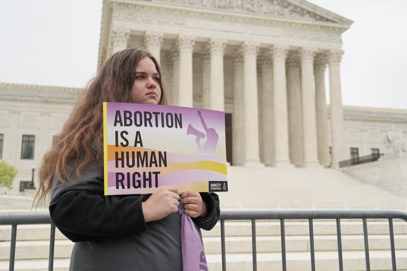 A young woman holds a sign that reads 'Abortion is a human right' in front the Supreme Court. Willy Lowry / The National
