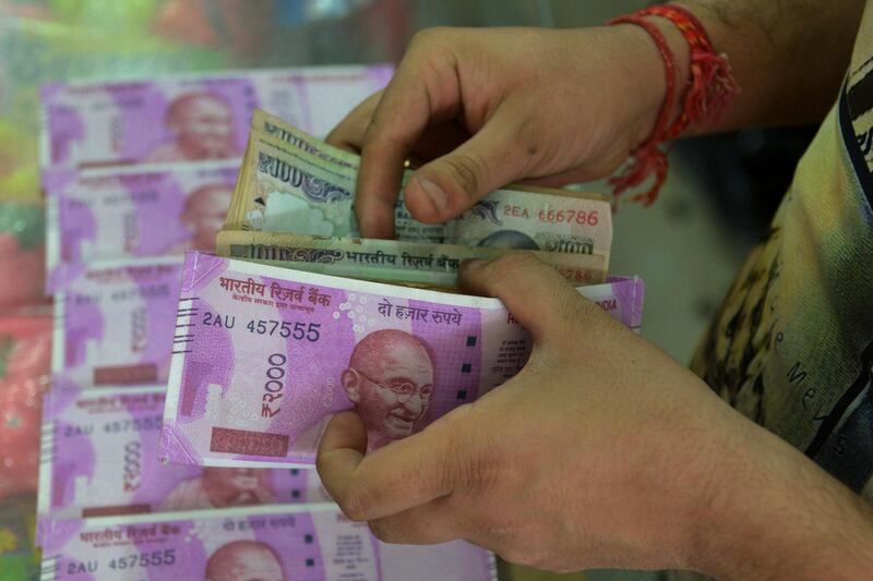 An Indian customer buys a wallet decorated with an image of the new Indian Rupee 2000 note, at a gift shop in Amritsar on March 24, 2017. / AFP PHOTO / NARINDER NANU