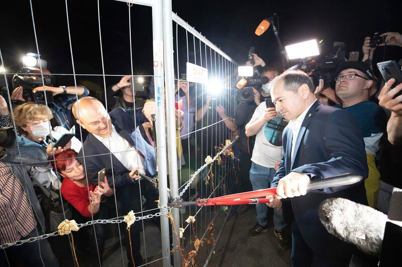 Lord Mayor of Gorlitz Octavian Ursu, center right, and Mayor of Zgorzelec, Poland, Rafal Gronicz, center left, together open the border fence on the Gorlitz Old Town Bridge in Gorlitz, Germany. dpa via AP