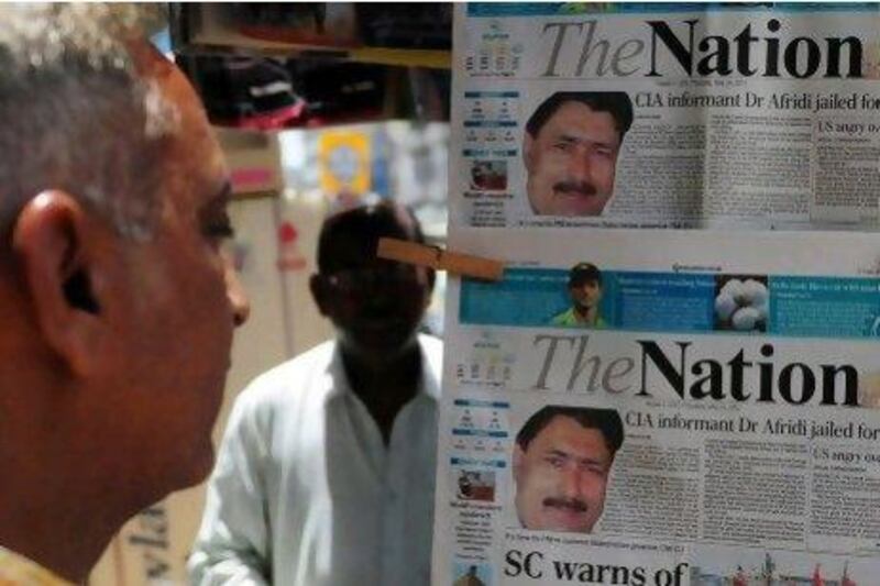 A man reads a newspaper in Karachi which headlines the sentencing of the Shakil Afridi, the Pakistani surgeon recruited by the CIA to help find Osama bin Laden, to 33 years in prison for treason.