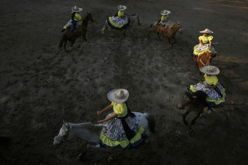 Women in charro costumes adorned with silver studs show off their lasso skills as their horses dance to a mariachi band, in Jalisco, Mexico. EPA