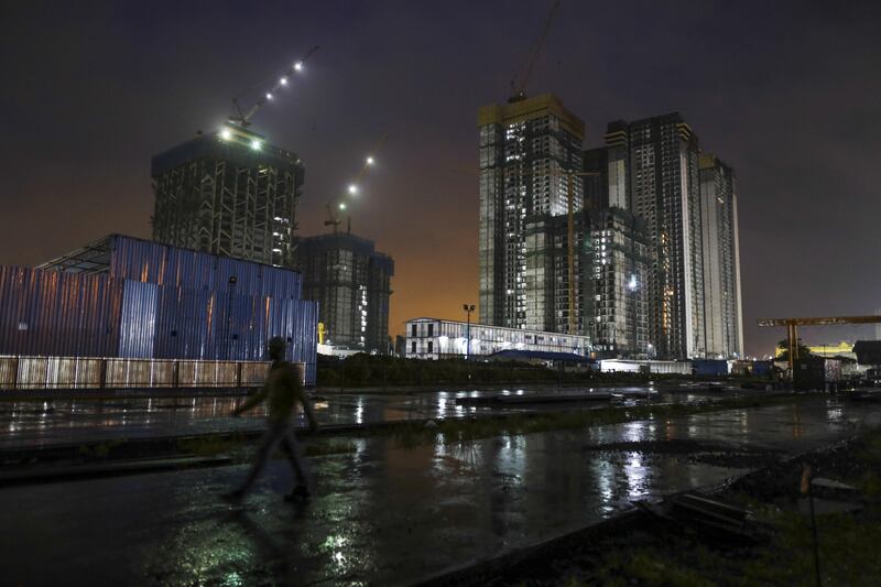 A worker walks through the Mumbai Metro Rail Corp. (MMRC) casting yard as buildings under construction stand illuminated at night in Mumbai, India, on Monday, Aug. 28, 2017. The expanding mega city's suburban railway is one of the most crowded and among the most dangerous in the world. That's why there's an 800 billion rupee ($12.5 billion) project under way to build a new, rapid transit system that will carry an estimated 7 million more passengers ��� making it busier than Metros in New York and London. Photographer: Dhiraj Singh/Bloomberg