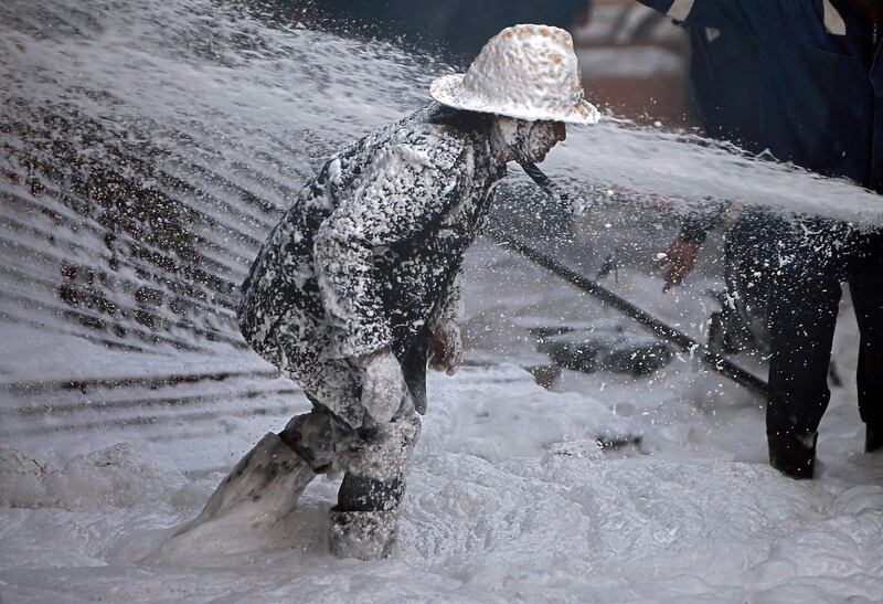A firefighter is covered with Aqueous Film Forming Foam as he tries to control a blaze in Ahmedabad. Reuters