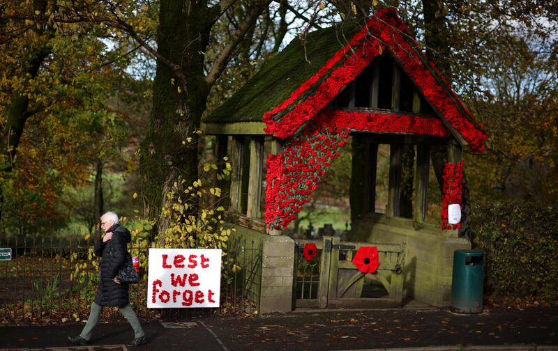 A woman walks past an installation made out of knitted poppies at the entrance to Christ Church in Burbage. Reuters
