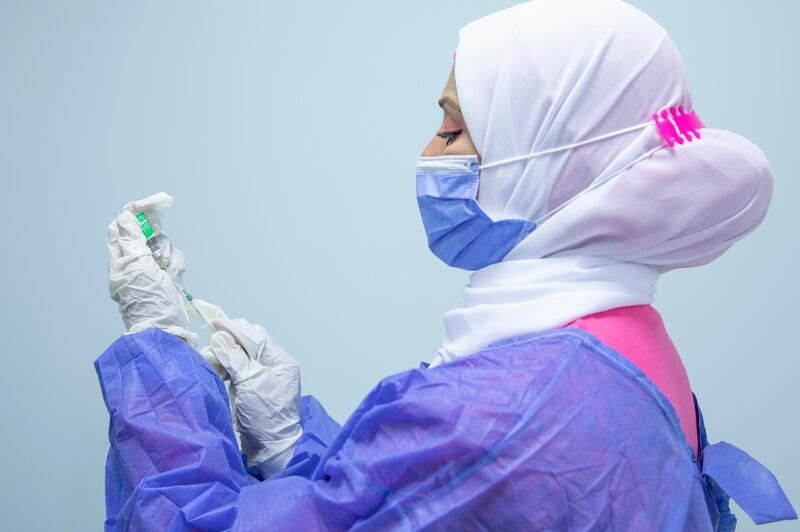 A nurse prepares the AstraZeneca COVID-19 vaccine to give to an elderly man, at Al-Nozha Hospital in Cairo, Egypt. AP Photo