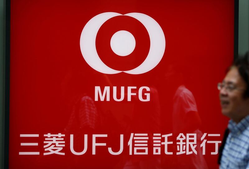 A man walks past in front of a sign board of Mitsubishi UFJ Trust and Banking Corporation, the asset management unit of Japan's Mitsubishi UFJ Financial Group Inc. (MUFG), in Tokyo, Japan July 31, 2017. REUTERS/Issei Kato