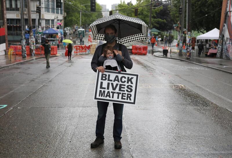 A man holds his child and a sign that reads 'Black Lives Matter' near Seattle Police Department East Precinct. Reuters