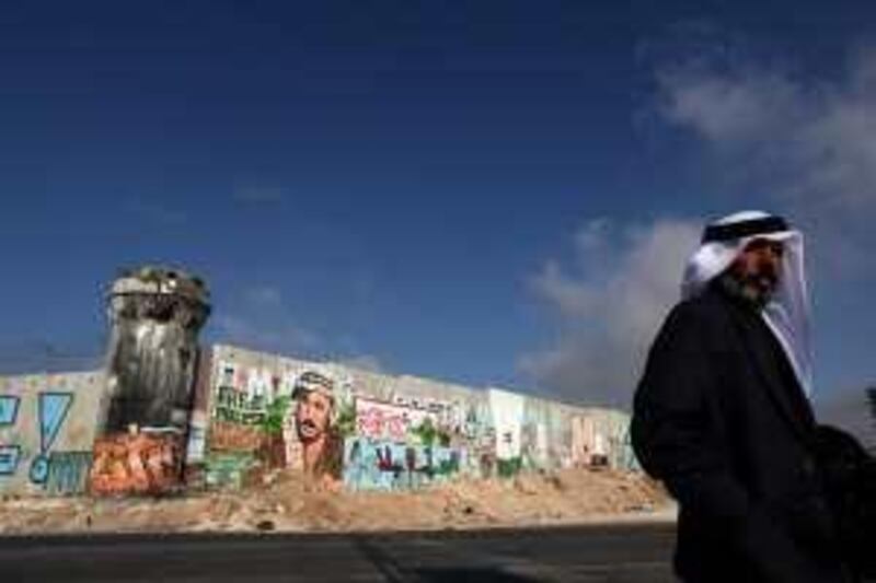 epa01786299 A Palestinian  man stands  next to a part of the controversial Israeli barrier at the Qalandiya checkpoint near the West Bank city of Ramallah, 07 July 2009.  EPA/PAVEL WOLBERG *** Local Caption ***  01786299.jpg