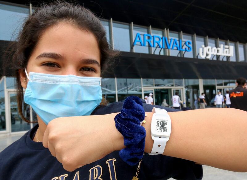 A Kuwaiti national, residing abroad, shows the tracking bracelet provided by authorities as she leaves at the Kuwait International airport in the capital upon her return as part of a repatriation plan on April 19, 2020, and ahead of being taken to mandatory home quarantine.  AFP