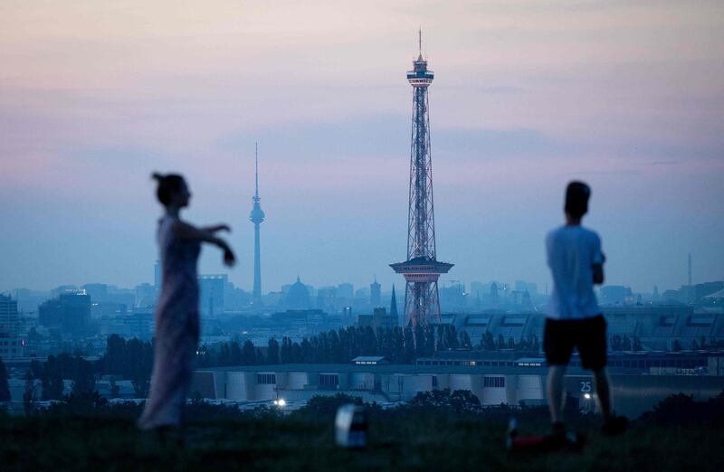 People standing at Drachenberg mountain wait for the sun to rise over Berlin on June 26, 2019, as in background can be seen landmarks of the German capital, the Fernsehturm (tv-tower, L) and the Funkturm (radio tower). Germany OUT
 / AFP / dpa / Kay Nietfeld

