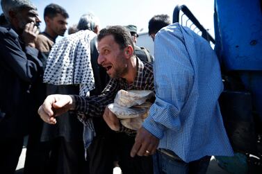 A Syrian man holds bread as Syrian authorities distributed bread, vegetables and pasta to Douma residents, in the town of Douma, the site of a suspected chemical weapons attack, near Damascus, Syria, Monday, April 16, 2018. Two days after Syrian troops declared Douma liberated from opposition fighters, a tour in the city showed the widespread destruction it has suffered since falling under rebel control six years ago. (AP Photo/Hassan Ammar)