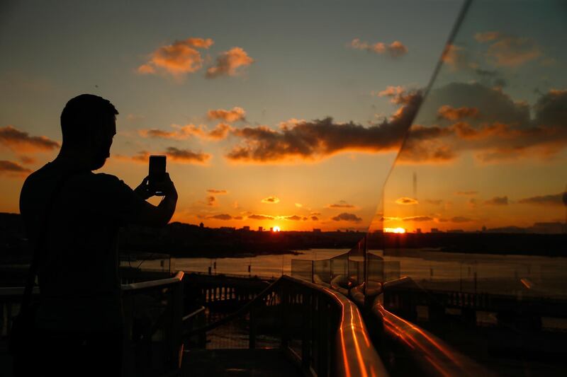 A young man takes photos of the sunset in Istanbul. AP Photo