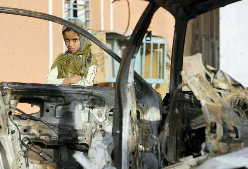 An Iraqi girl looks at a wrecked car in Baghdad's Sadr City on April 20, 2008, struck by US missiles during fierce fighting with al-Mahdi army militia overnight. Loudspeakers at mosques in Baghdad's Shiite bastion Sadr City blared out a call to arms soon after radical cleric Moqtada al-Sadr warned of a new uprising of his militiamen, residents said today. Iraqi security and medical officials, meanwhile, reported another eight people killed overnight in clashes between militiamen and US and Iraqi forces in the embattled township, where battles have been raging since late March. AFP PHOTO/AHMAD AL-RUBAYE / AFP PHOTO / AHMAD AL-RUBAYE