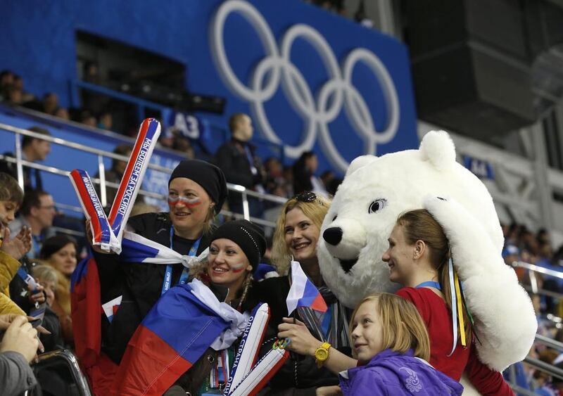 Ice hockey fans pose for a photograph with an Olympic bear mascot during the women’s preliminary hockey game between USA and Finland. Jim Young/Reuters