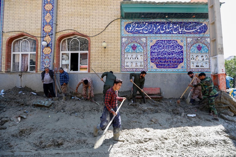 Workers clear the mud from outside a mosque following a flash flood and mudslide in Firuzkuh. AFP