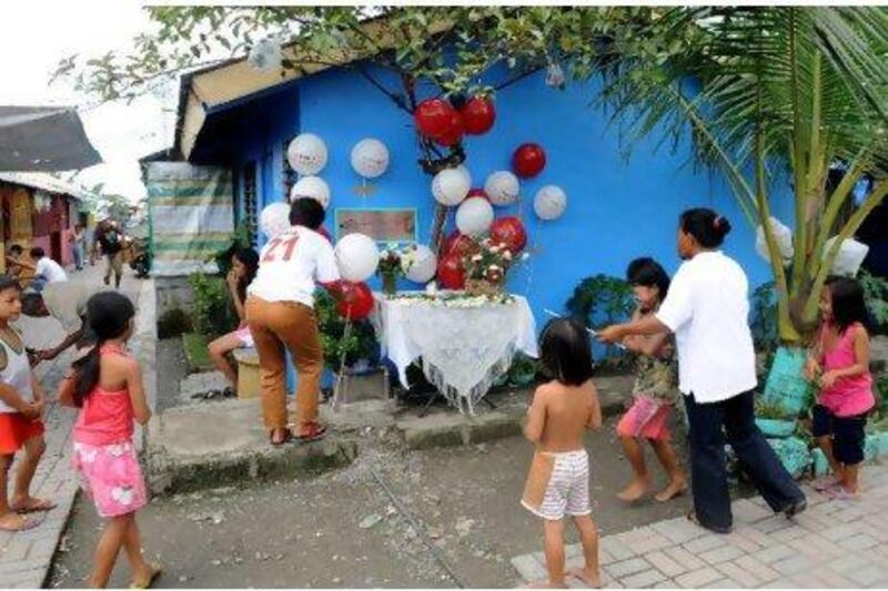 Residents from the Mary Rose Abad GK village, a low-cost housing community in Manila named after one of the victims of the 9/11 attacks in New York, offer flowers, balloons and light candles yesterday in memory of Mary Rose Abad, a US woman whose Filipino-born husband built the community as a memorial to his wife. Jay Directo / AFP Photo