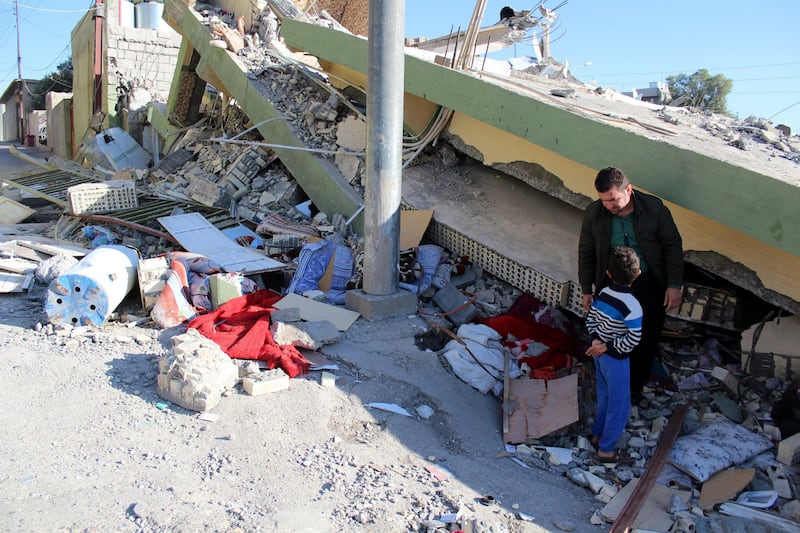 epa06326236 An Iraqi Kurdish man stands with his son near a building destroyed in earthquake at Darbandikhan town, near Sulaymaniya city, northern Iraq, 13 November 2017. At least six people were killed and 50 others injured in Iraqi Kurdistan's Sulaymaniyah when a powerful magnitude 7.2 earthquake hit the region along the border between Iran and Iraq on 12 November, local officials said. At least 328 inhabitants were killed and another 3,950 injured in Iran's Kermanshah province bordering Iraq.  EPA/AFAN ABDULKHALEQ