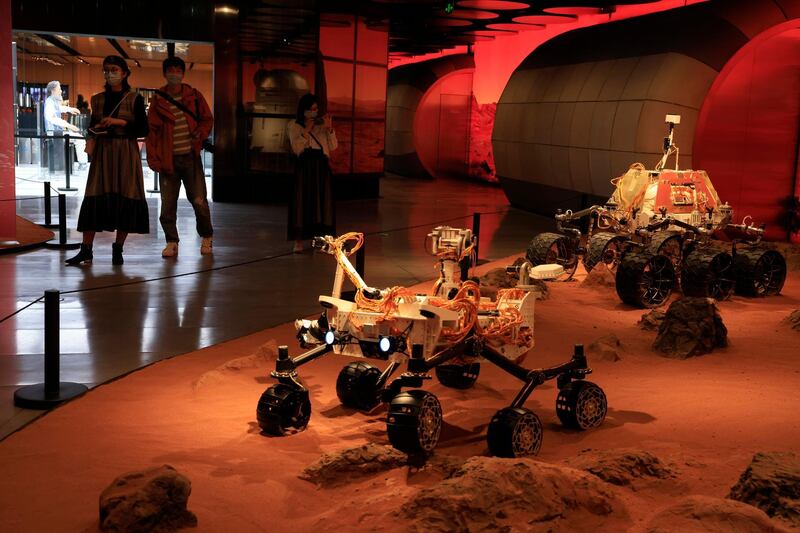 Visitors pass by an exhibition depicting rovers on Mars in Beijing. AP Photo