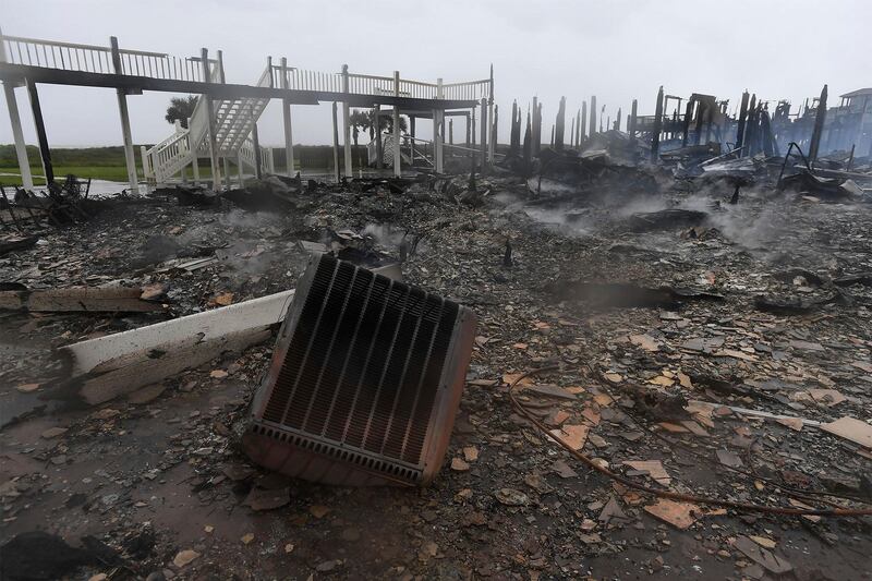 Debris from the charred remains of three Bolivar, Texas, beach cabins, destroyed by a fire that broke out when Hurricane Harvey made landfall, lies on the ground.  Fire officials are investigating the cause of the accident. No injuries were reported during the blaze. Guiseppe Barranco / The Beaumont Enterprise via AP