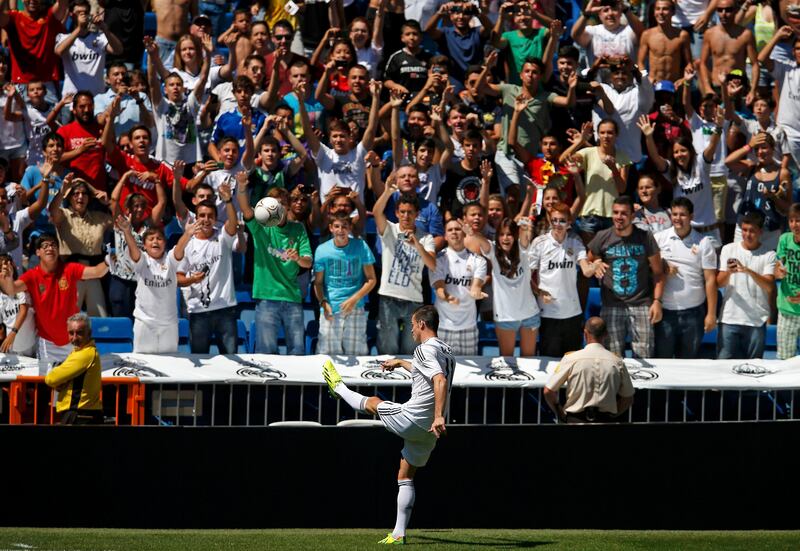 Gareth Bale of Wales kicks a ball to fans at the Santiago Bernabeu stadium in Madrid, September 2, 2013. Thousands of Real Madrid fans flocked to the Bernabeu to welcome Gareth Bale on Monday after the nine-times European champions sealed the purchase of the Wales winger from Tottenham Hotspur for what the London club said was a world record fee.    REUTERS/Sergio Perez (SPAIN  - Tags: SPORT SOCCER BUSINESS)   *** Local Caption ***  JMR16_SOCCER-SPAIN-_0902_11.JPG
