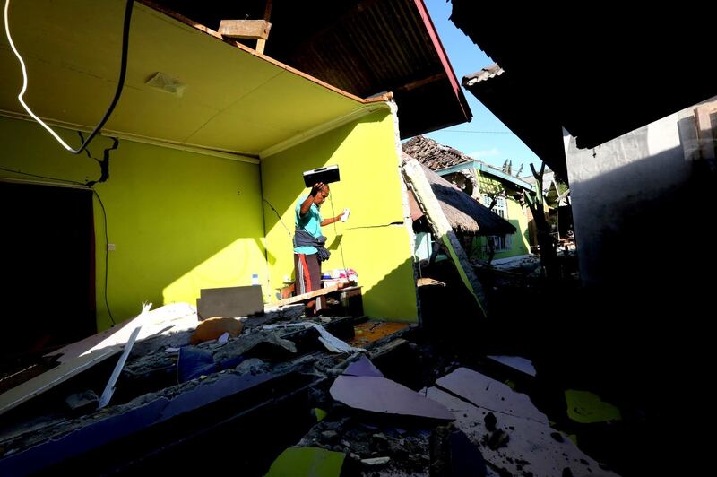 Usable items are salvaged from a home destroyed in an earthquake in North Lombok, Indonesia. Tatan Syuflana/AP Photo