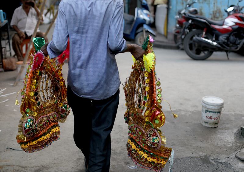 A devotee carries decorative crowns of the deity Kali ahead of Diwali in Kolkata. EPA