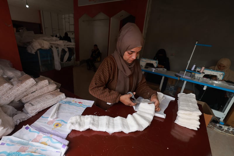 A Palestinian woman cuts material to be used for sewing nappies at a workshop in Rafah. AFP