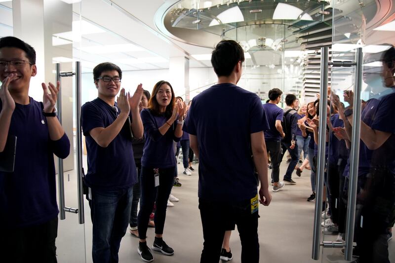 Staff members clap customers through the door at an Apple Store in Shanghai. Aly Song / Reuters