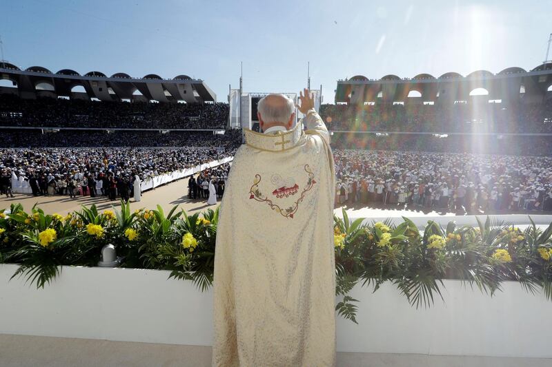 A priest waves to the crowd as he waits for the arrival of Pope Francis at Zayed Sports City. AP Photo