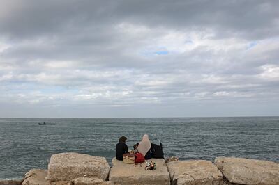 Palestinian women sit together at the seaport of Gaza City on October 18, 2021. AFP