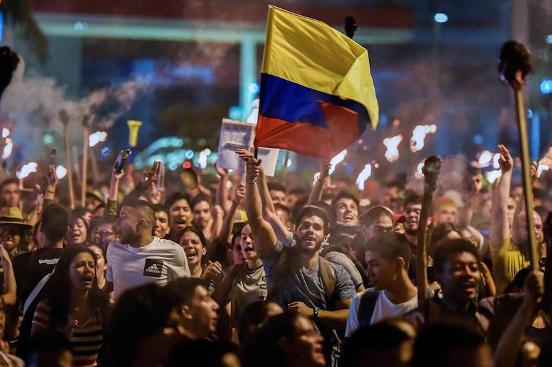 Students march with torches and a Colombian flag on the eighth consecutive day of protests against the government of Colombian President Ivan Duque in Cali, Colombia.  AFP