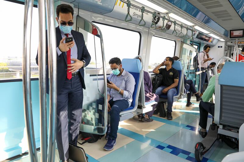 Commuters wearing protective face masks use smartphones on the metro in Dubai on March 5. Bloomberg