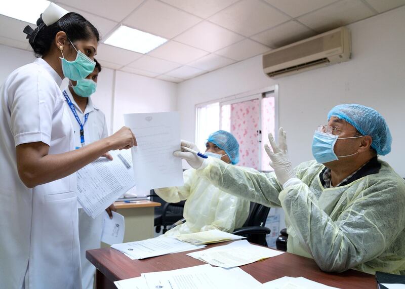 An expatriate nurse (L), takes a coronavirus clearance certificate from a doctor, after returning from a vacation, following the outbreak of the virus, at a health clinic in Subhan, Kuwait March 9, 2020. REUTERS/Stephanie McGehee