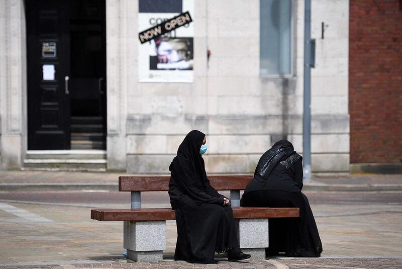 Women wearing a face covering sit on a bench in Blackburn. AFP