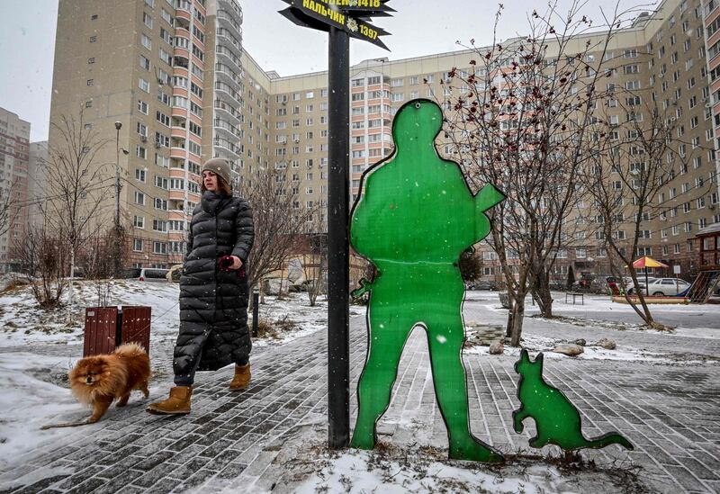 A woman walks a dog past the so-called "people's installation to a Russian soldier" nicknamed the "polite people" created by residents in the backyard of their apartment building in the town of Podolsk, outside Moscow. AFP